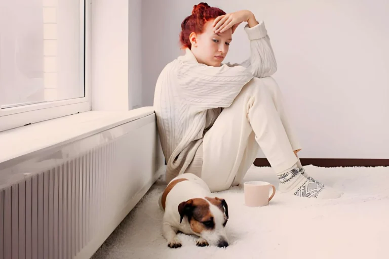 Une femme regarde pensivement un chien qu'elle vient d'adopter, assis à côté d'elle.